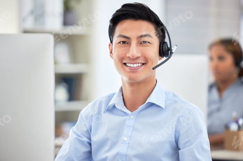 Preview: Portrait of asian call centre agent talking on headset while working on computer in office. Confide