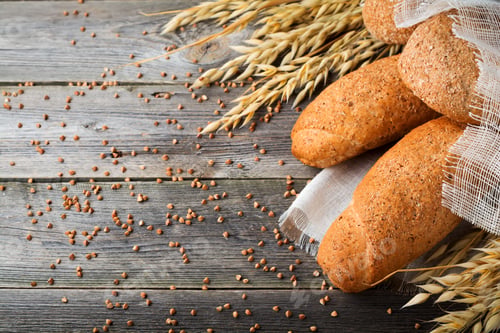Preview: Bread wholemeal oat and buckwheat flour with spikes on old wooden background. Selective focus