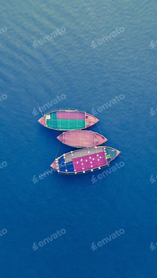 Preview: Aerial shot of three colorful boats in the blue ocean water.
