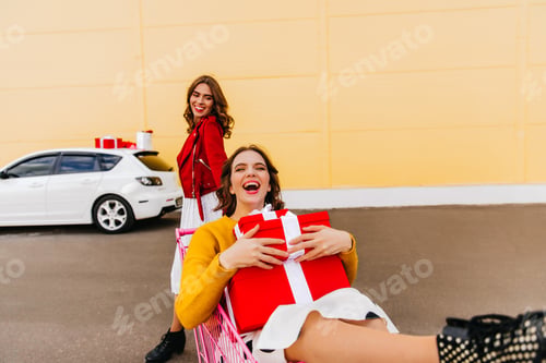 Preview: Carefree girls buying presents for holiday. Outdoor shot of laughing female friends