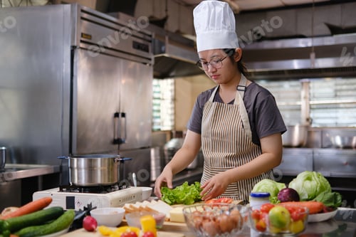 Preview: Focused chef preparing clean food ingredients from organic farm produce in a professional kitchen.
