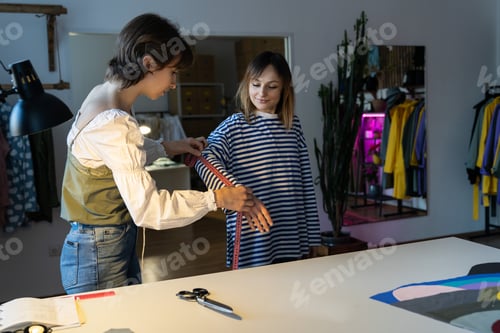 Preview: Fashion designer woman takes measurements with measuring tape of client before tailoring clothes