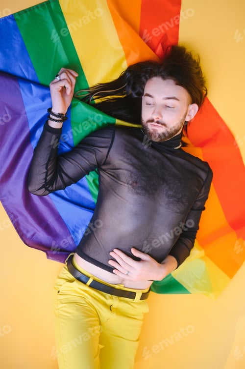 Preview: Gay man hold rainbow striped flag isolated on colored background studio portrait.