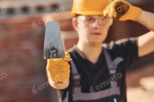 Preview: Portrait of construction worker in uniform and safety equipment that standing on building