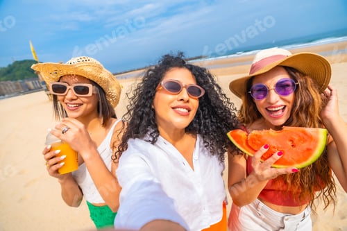 Preview: Three women are smiling and holding watermelons on a beach