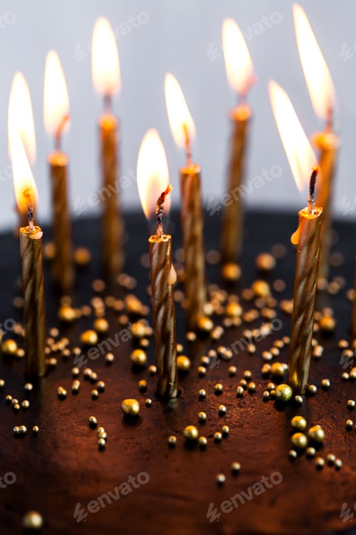 Visualização: Bolo de aniversário redondo preto com velas douradas acesas sobre fundo branco