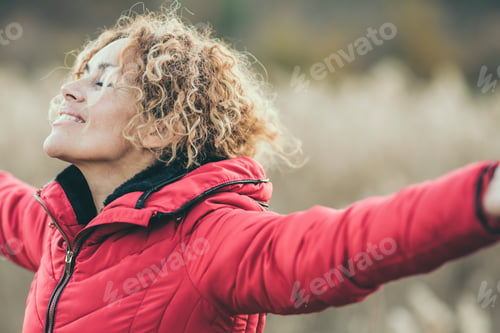 Preview: One happy woman outstretching arms in outdoor leisure activity with nature field in background.