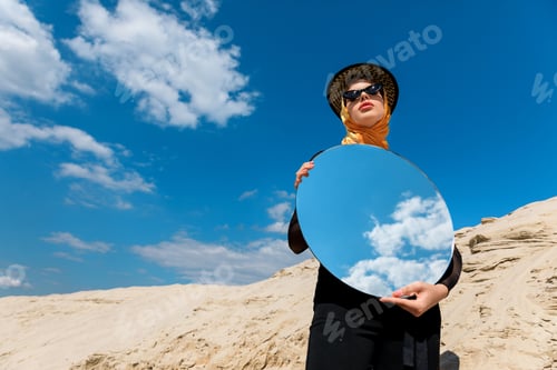 Preview: stylish attractive girl posing with round mirror and reflection of cloudy sky
