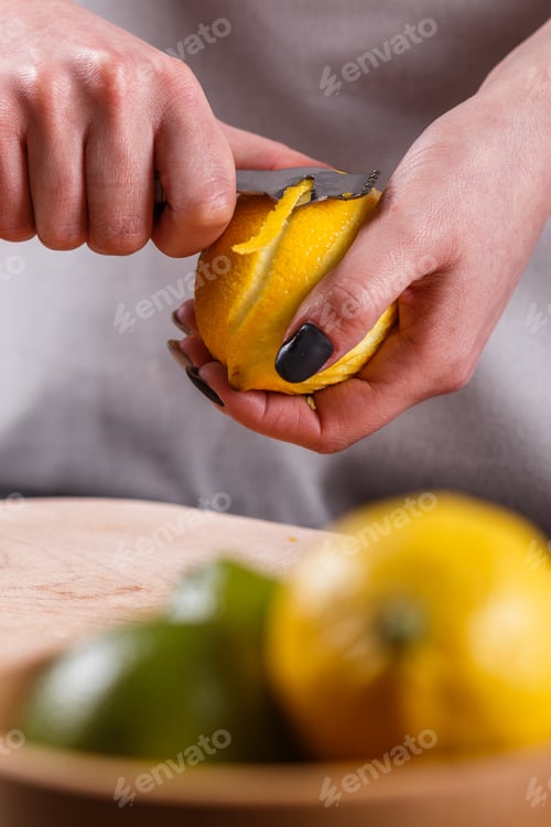 Preview: young woman in a gray aprons cuts lemon zest