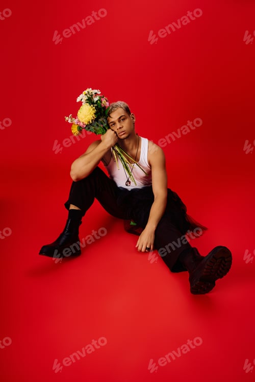 Preview: Young man in trendy attire showcasing vibrant style against a bold red backdrop