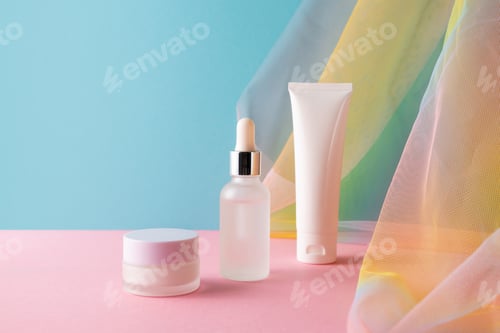 Preview: Serum, facial cleanser and moisturizer cream on blue pink background with colorful rainbow fa