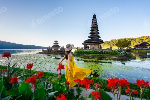 Preview: Young woman tourist relaxing and enjoying the beautiful view at Ulun Danu Beratan temple in Bali