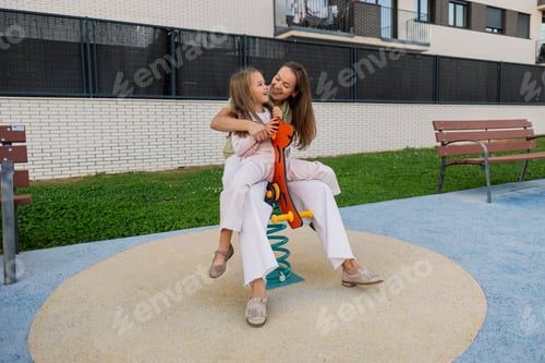 Preview: Mother daughter playing laughing together on playground spring rider