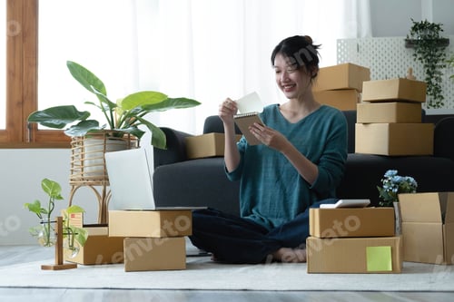 Vista previa: Las mujeres asiáticas escriben notas de pedidos de productos con una cara sonriente en el concepto de pyme, negocio de comercio electrónico