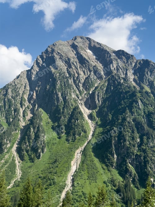 Preview: Mountain peak standing tall with green slopes