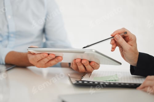 Preview: Closeup of two businesspeople working on a digital tablet in a meeting together at work. Business p