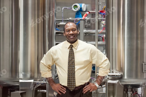 Preview: African American male manager in a shirt and tie standing in front of processing tanks
