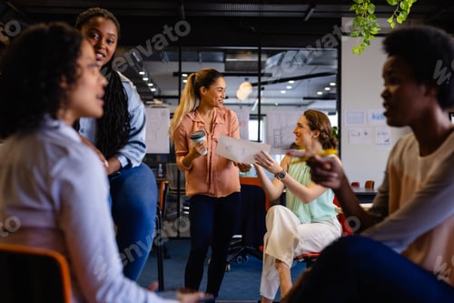 Preview: Diverse female colleagues in discussion using tablet in casual office meeting