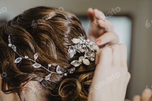Preview: Bride fixing a beautiful hairpiece with teardrop crystal and flowers on the head