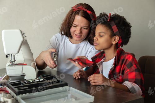 Preview: Caucasian Mom and mixed-race daughter sew clothes for dolls at home.Family leisure.Mother's Day.