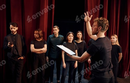 Preview: Group of actors in dark colored clothes on rehearsal in the theater