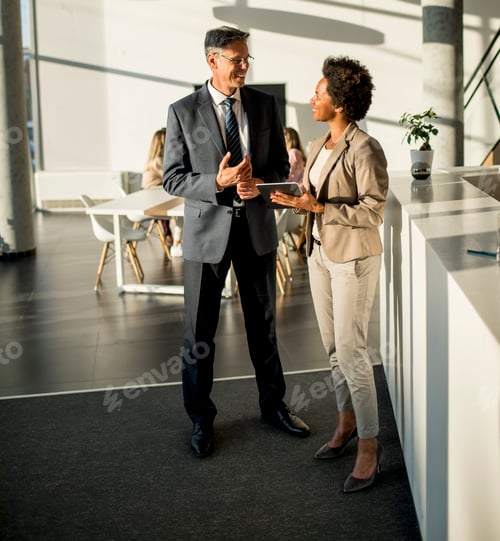 Preview: Multiethnic business people using digital tablet while standing in the office