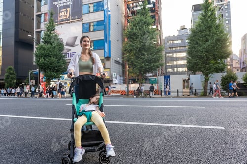 Preview: Asian mother pushing baby stroller car walking in the city of Japan.