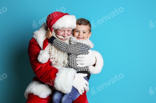 Preview: Little boy hugging authentic Santa Claus on color background