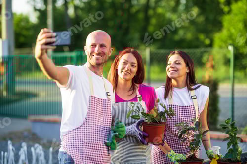 Preview: Garden center workers taking selfie holding plants