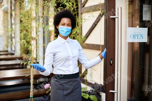 Preview: Happy black waitress with protective face mask reopening cafe after COVID-19 epidemic.