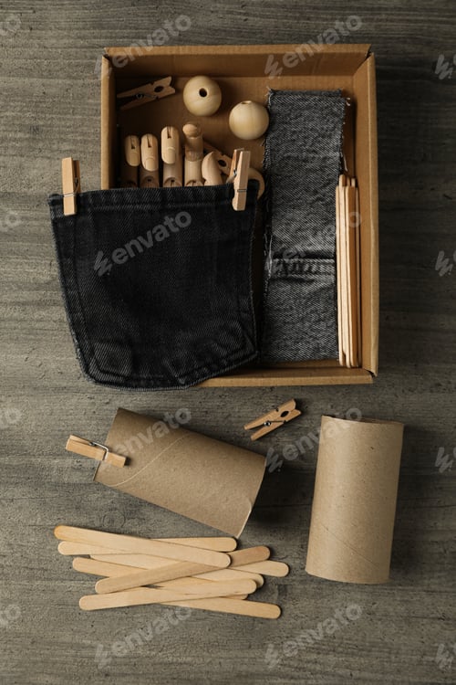 Preview: Pieces of denim fabric, paper rolls and box on wooden background, top view