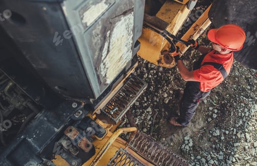 Preview: Worker Repairing Heavy Machinery at Construction Site During Daylight