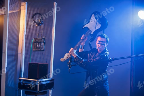 Preview: Cool stylish musician holding bass guitar to smash