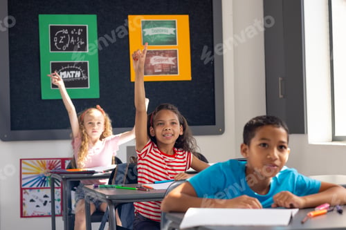 Preview: In school, diverse young students raising hands in the classroom, eager to answer