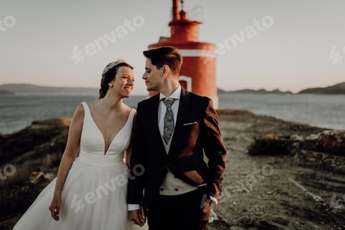 Preview: Moody portrait of a just married couple against a lighthouse