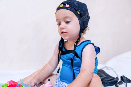 Preview: Baby patient playing in bed during EEG examination