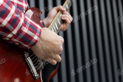 Preview: A stylish young guy plays the guitar on a dark background