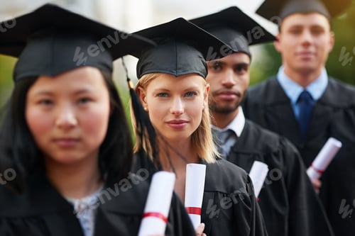 Preview: A group of college graduates standing in cap and gown and holding their diplomas