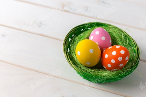Preview: Colorful eggs in a green basket on a wooden surface for an Easter celebration