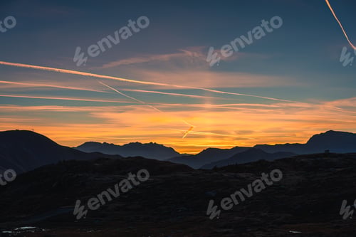 Preview: Colorful sky with contrail or condensation trail over mountain range