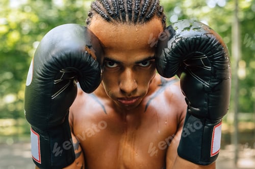 Preview: Close up portrait of a sweated kickboxer with gloves and mouth guard looking at the camera