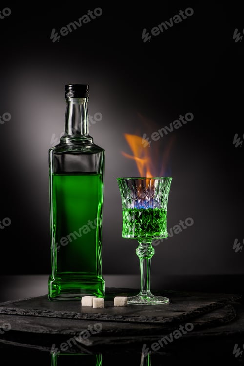 Preview: close-up shot of bottle and glass of burning absinthe on dark background