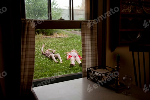 Preview: View through window of boy and and girl lying in garden