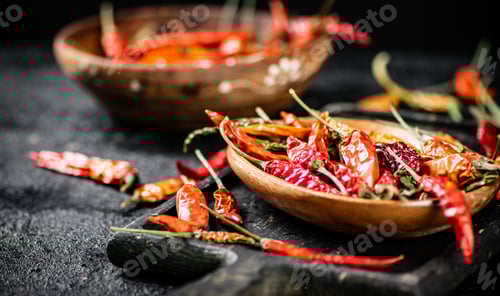 Preview: Multicolored pods of dried chili peppers on a cutting board.