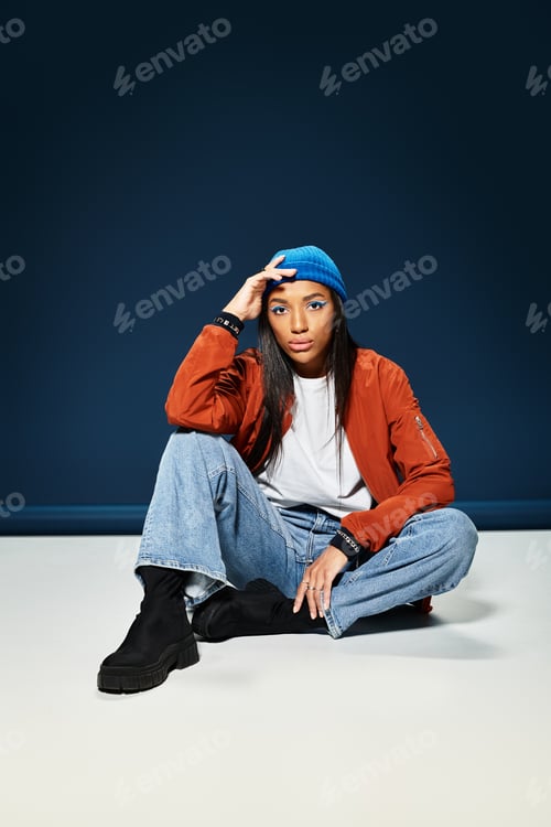 Preview: A young woman in stylish autumn attire poses thoughtfully against a dark backdrop