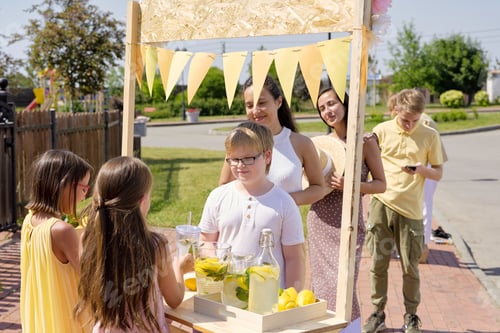 Preview: Two little girls standing by wooden stall and selling fresh self-made lemonade