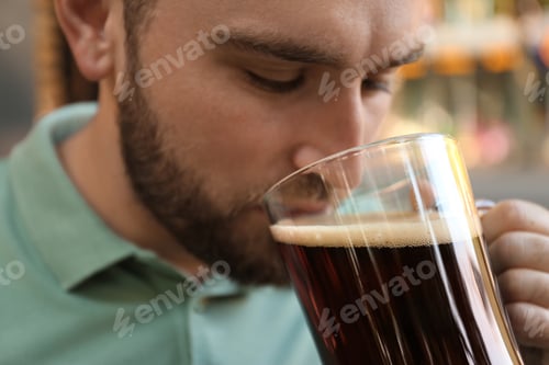 Preview: Handsome man with cold kvass outdoors, closeup. Traditional Russian summer drink