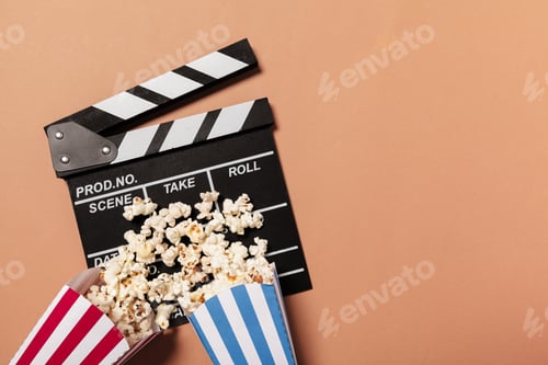 Preview: Popcorn spills from boxes next to a film clapperboard on a plain background