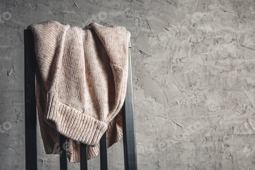 Preview: Knitted beige sweater on the back of a white wooden chair