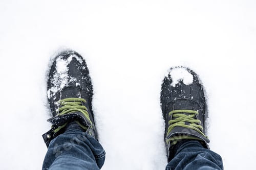 Preview: Men's feet in boots in deep snow, top view.